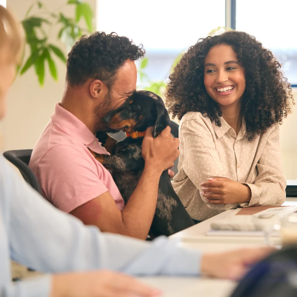 Woman Working In Office Based Business Training Man Holding Pet Dachshund Dog
